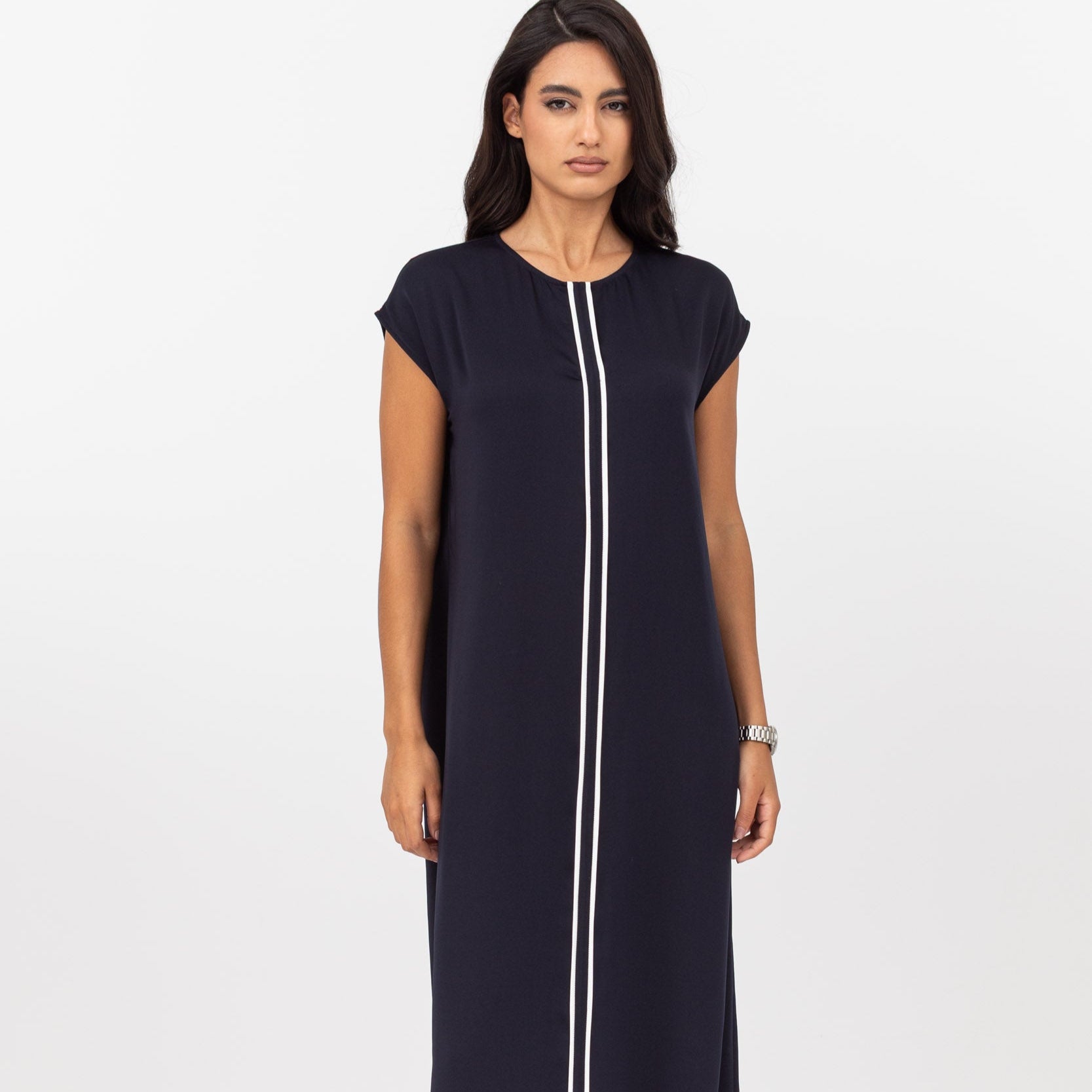 Woman wearing a navy blue dress with a white lines on a white background
