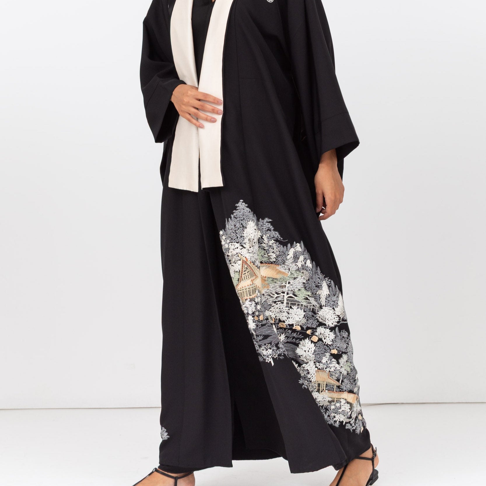 Woman wearing a black kimono abaya with floral embroidery on a white background
