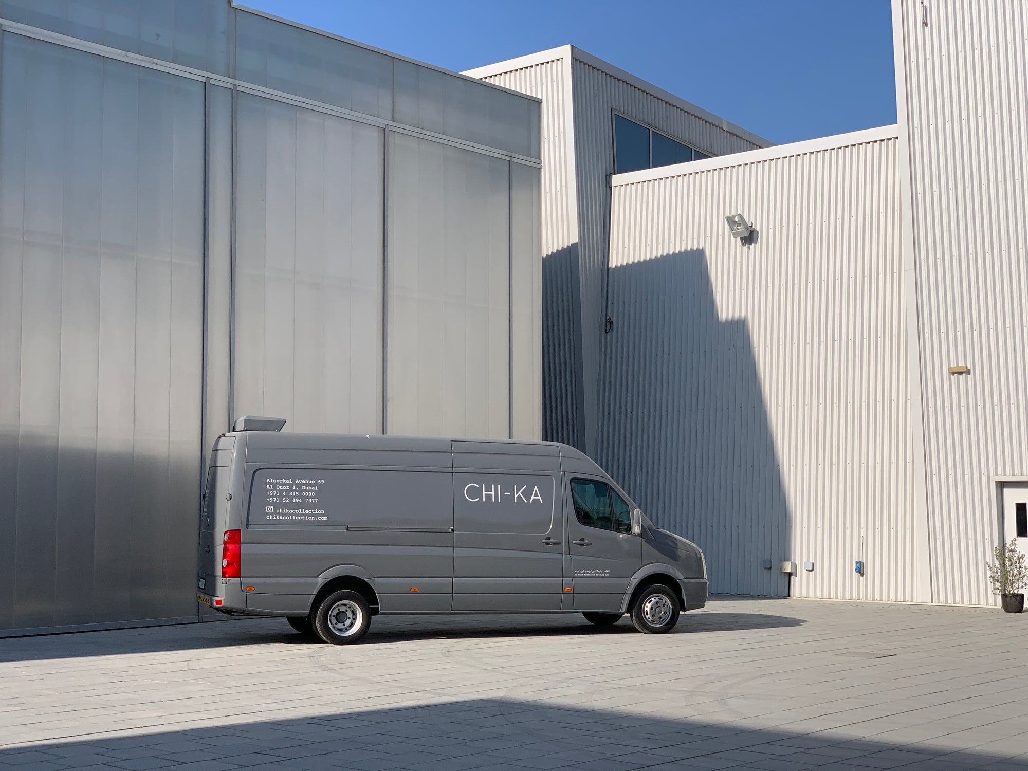 Gray van with 'CHI-KA' branding parked in front of a modern building.